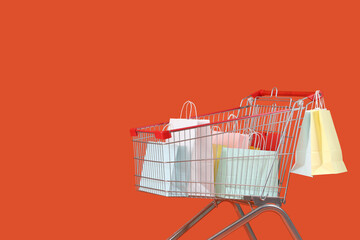 Shopping bags in cart on orange background
