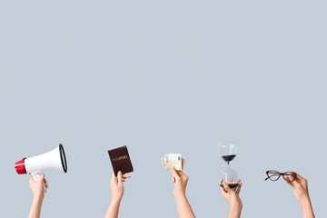 Female hands holding hourglass, megaphone, law book and money on grey background