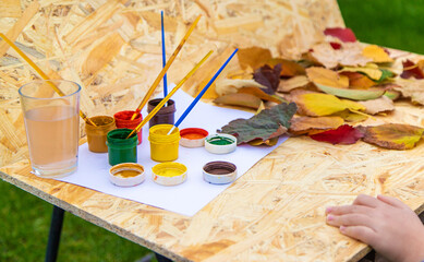 Fototapeta premium Child drawing autumn leaves. Selective focus.