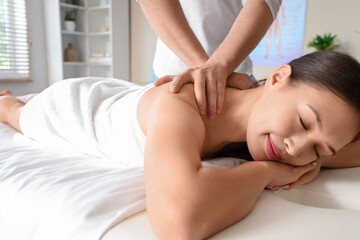 Young Asian woman getting massage in spa salon, closeup