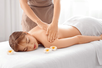 Young woman undergoing massage procedure in spa salon