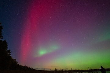 Northern Lights, Aurora Borealis. Night sky by the lake, geomagnetic storm G4