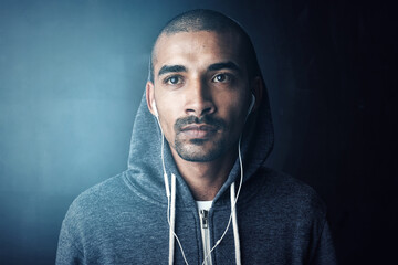 Gym, thinking and man in studio with earphones, hoodie and training ideas for fitness workout. Health, wellness and athlete on music app for exercise, inspiration and confidence on dark background