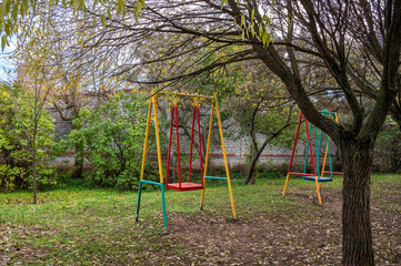 Empty swings in the autumn courtyard.