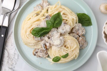 Delicious pasta with mushrooms and basil served on white tiled table, flat lay