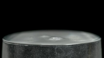 White powder is poured into a glass beaker with water on black background, medicine medical concept, macro, close up