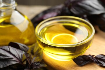 Cooking oil in bowl and red basil on wooden board, closeup
