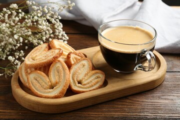Tasty french palmier cookies, coffee and gypsophila flowers on wooden table, closeup