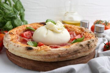 Delicious pizza with burrata cheese, basil, tomatoes and ham on table, closeup