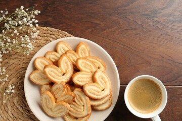 Delicious palmier cookies with coffee on wooden table, flat lay