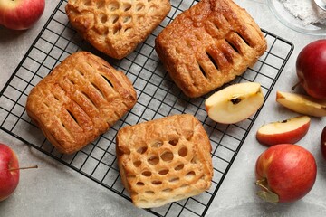 Delicious puff pastries with fruit filling and apples on grey table, top view