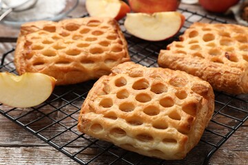 Delicious puff pastries with fruit filling and apples on wooden table, closeup