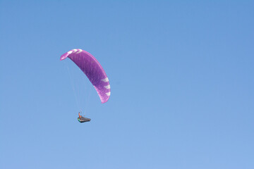 Flying paraglider in sky over mountains ridge