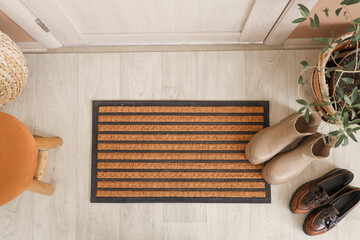 Door mat with shoes on floor in hallway, top view