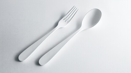 A minimalistic spoon and fork set placed diagonally on a white surface, with clean, simple lines reflecting an elegant, upscale dining experience