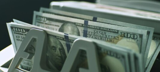 Close-up view of money counting machine counting American dollar banknotes for currency exchange in slow-motion - Powered by Adobe