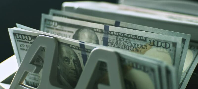 Close-up view of money counting machine counting American dollar banknotes for currency exchange in slow-motion