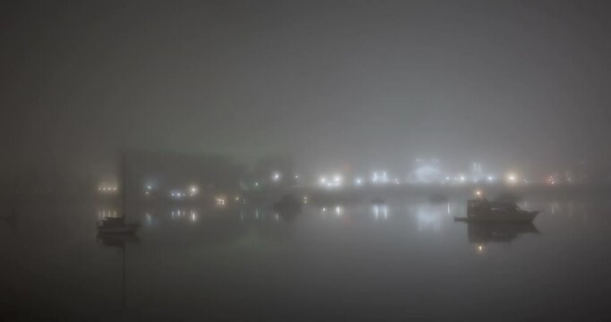 boats in the harbor during a foggy winter night