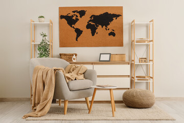 World map on wall, armchair, chest of drawers and shelving units in interior of living room