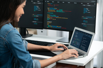 Smiling young Asian in IT developer creating with typing online information on laptop with coding...