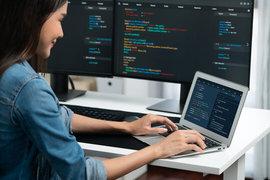 Smiling young Asian in IT developer creating with typing online information on laptop with coding program data of application, wearing jeans shirt. surrounded by safety analysis two screen. Stratagem.