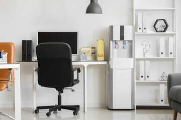 Interior of light office with workplace, shelf unit and water cooler
