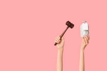 Woman holding auction gavel and antique vase on pink background