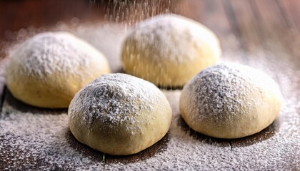 a close up of four dough balls with powdered sugar on top