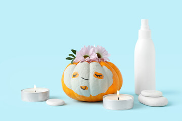 Pumpkin with drawn face, clay mask, bottle of cosmetic product, candles and bottle of cosmetic...