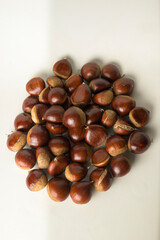 Chestnuts with a white background in a top view, freshly picked, ready to be consumed vertically