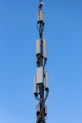 A tall communication tower stands under a clear blue sky in a rural area, symbolizing connectivity and progress