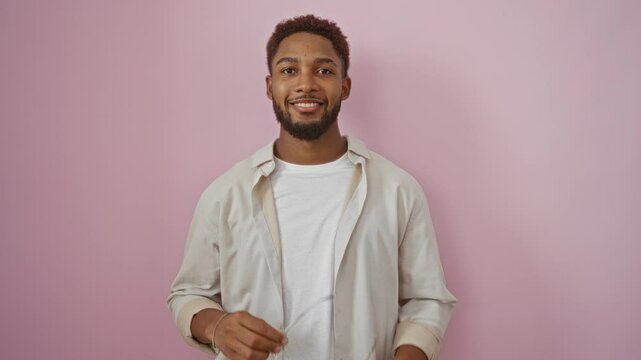 Handsome young man smiling and removing glasses against an isolated pink background