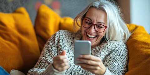 Fototapeta premium Elderly Woman Engrossed in Smartphone on Couch