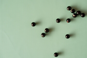 Overhead View of Black Marbles on Mint Green Background – Ideal for Textures and Backgrounds
