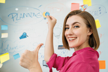 Young beautiful businesswoman putting thumb up while finding a solution to solve financial problems by using mind map and colorful sticky note. Creative business concept. Closeup. Immaculate.