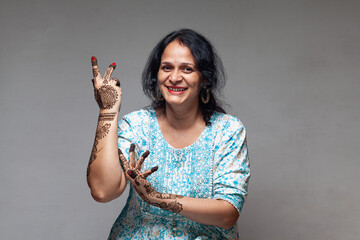 A joyful Indian woman showcasing her beautiful henna design in a dancing posture, captured during...