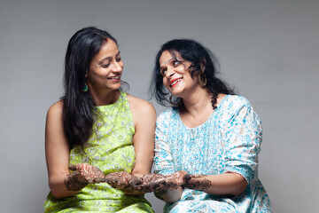 Two joyful Indian women show their beautiful henna designs, captured during the Karva Chauth...