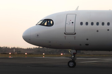 White passenger airplane along airport runway at dusk
