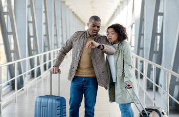 Stressed Young african couple Late For Flight, Upset Young Spouses Standing At Airport Terminal And...