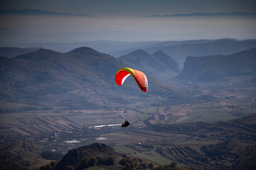 red paraglider flying over mountain