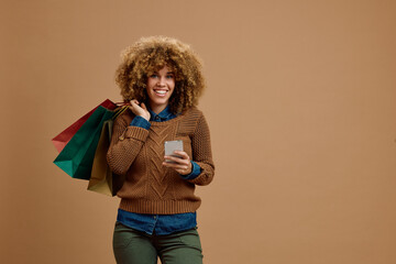 Beautiful mixed race woman with shopping bags using cell phone and looking at camera.