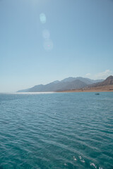 Serene Coastal Landscape: Tranquil Waters and Majestic Mountains Under a Clear Blue Sky
