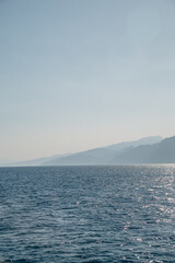 Serene Coastal Landscape: Tranquil Waters and Majestic Mountains Under a Clear Blue Sky