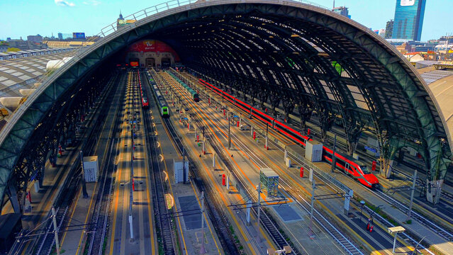 Aerial view of the station. Trains arrive at the station. An old wide arched structure of metal and glass above the station pillars. Tourism. Skyline with tall buildings. Italy, Milan, 29.10.2024 