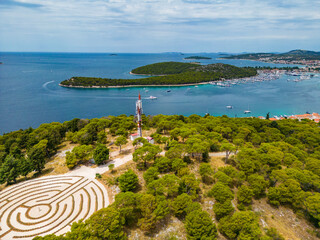 Aerial view of beautiful, turquoise bay beneath hills covered in pine forest at the town of...