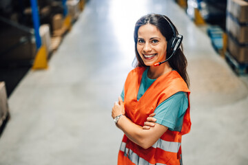 Smiling warehouse worker wearing headset with arms crossed