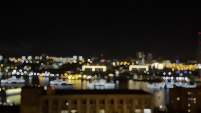 Bokeh blurred twinkling night city lights from buildings near bay water