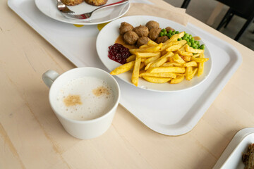 Meatballs with french fries, green peas, bechamel sauce and cranberry jam, meat balls on white plate
