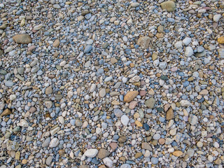 Colorful pebbles of various sizes and shapes, lying on the river shore