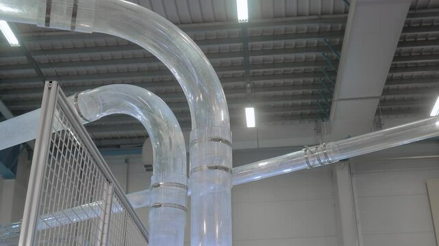 Vacuum tube conveyor system of paper cup making machine for transporting finished coffee cups and preform cup blanks at plastic factory, exhibition - close up. Industrial and production line concept